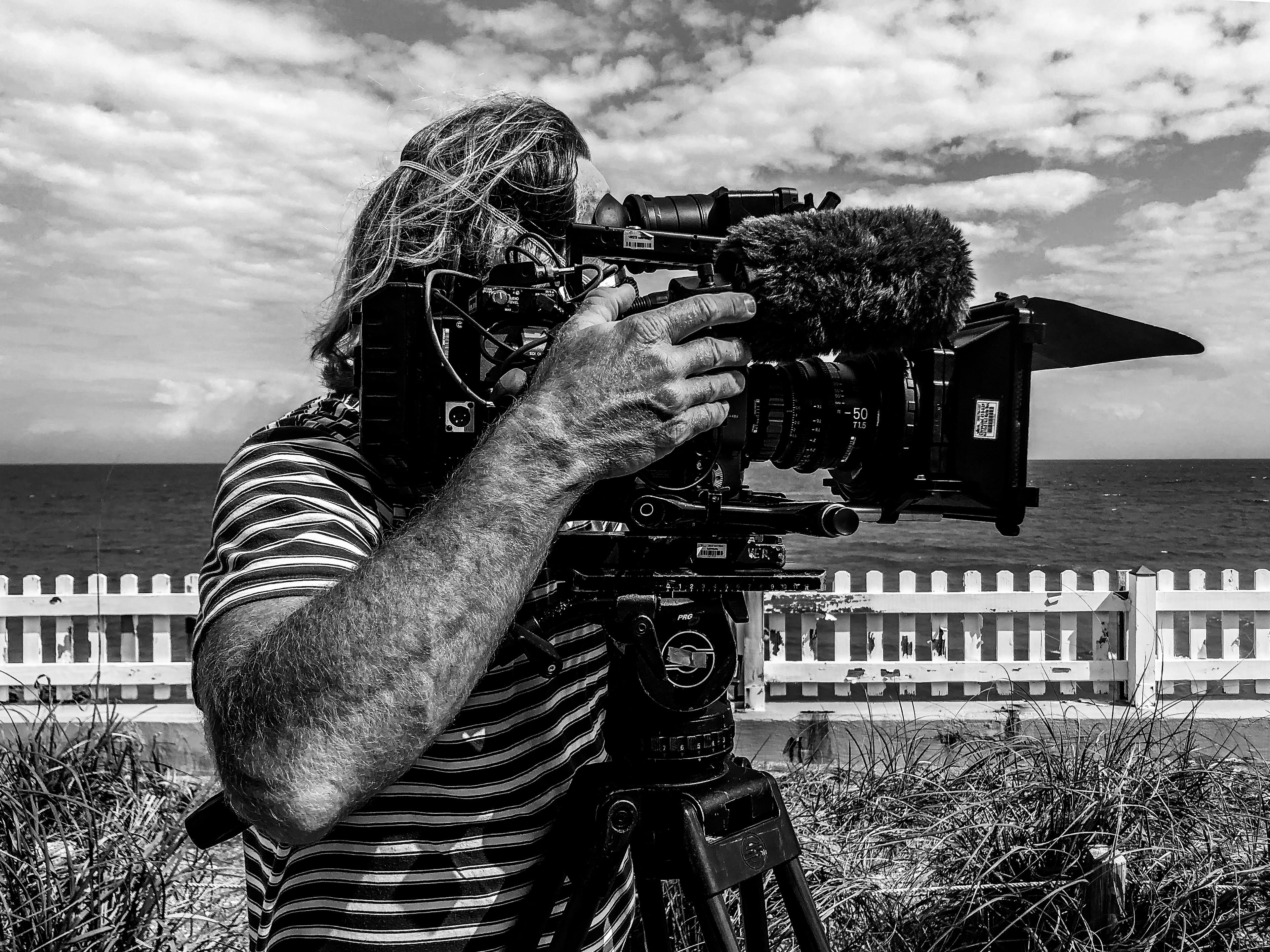 Filmmaker operating cinema camera by the ocean